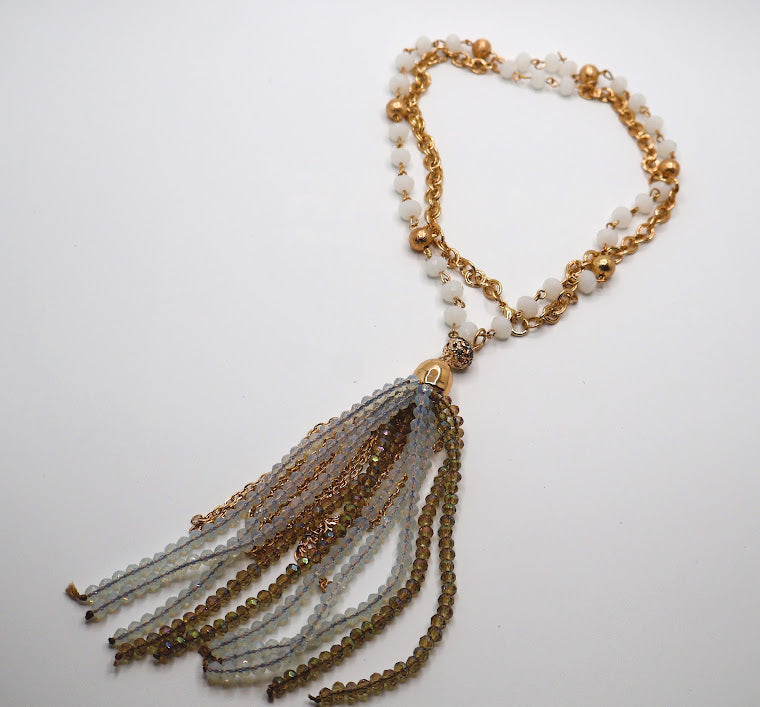 Necklace featuring a strand of soft ivory beads adorned with golden accents, this exquisite piece flows into a dazzling tassel of shimmering gold and crystal strands.