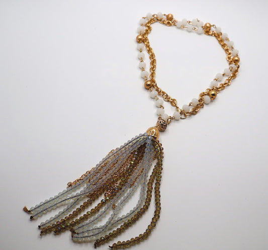 Necklace featuring a strand of soft ivory beads adorned with golden accents, this exquisite piece flows into a dazzling tassel of shimmering gold and crystal strands.