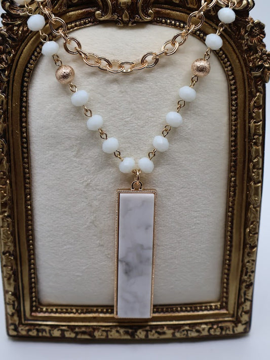 Necklace with a marble pendant,  blend of gold beads, and shimmering chain.
