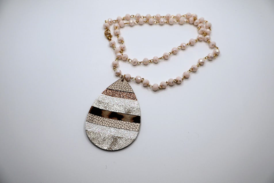 Necklace with  teardrop pendant adorned with a mix of shimmering gold, soft neutrals, and a playful leopard print.