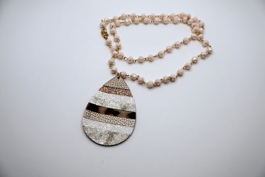 Necklace with teardrop pendant adorned with a mix of shimmering gold, soft neutrals, and a playful leopard print.