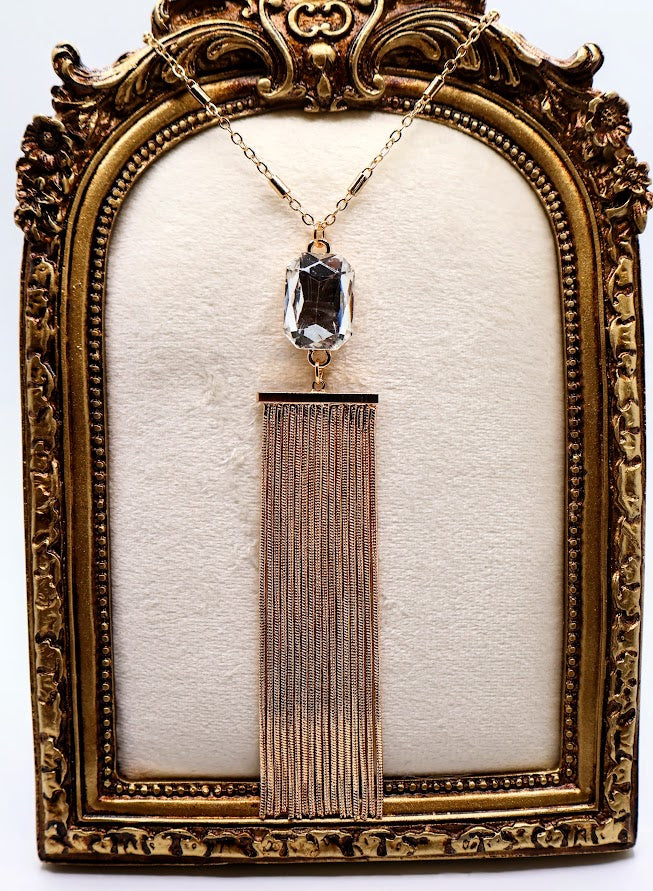 Necklace features a stunning crystal pendant that sparkles with every movement, elegantly paired with a flowing golden tassel.