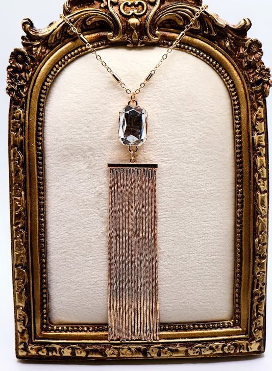 Necklace features a stunning crystal pendant that sparkles with every movement, elegantly paired with a flowing golden tassel.