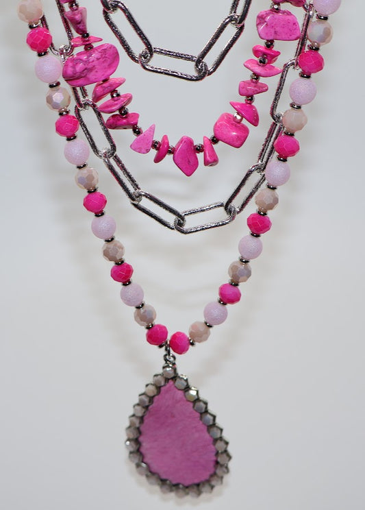 Necklace combines bold pink beads, silver chains, and a stunning teardrop pendant accented with sparkling rhinestones.