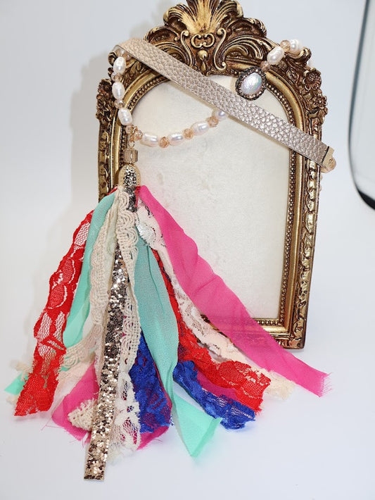 Multi-colored necklace cascade of colorful fabric ribbons, accented by shimmering pearl-like beads and a delicate gold chain.
