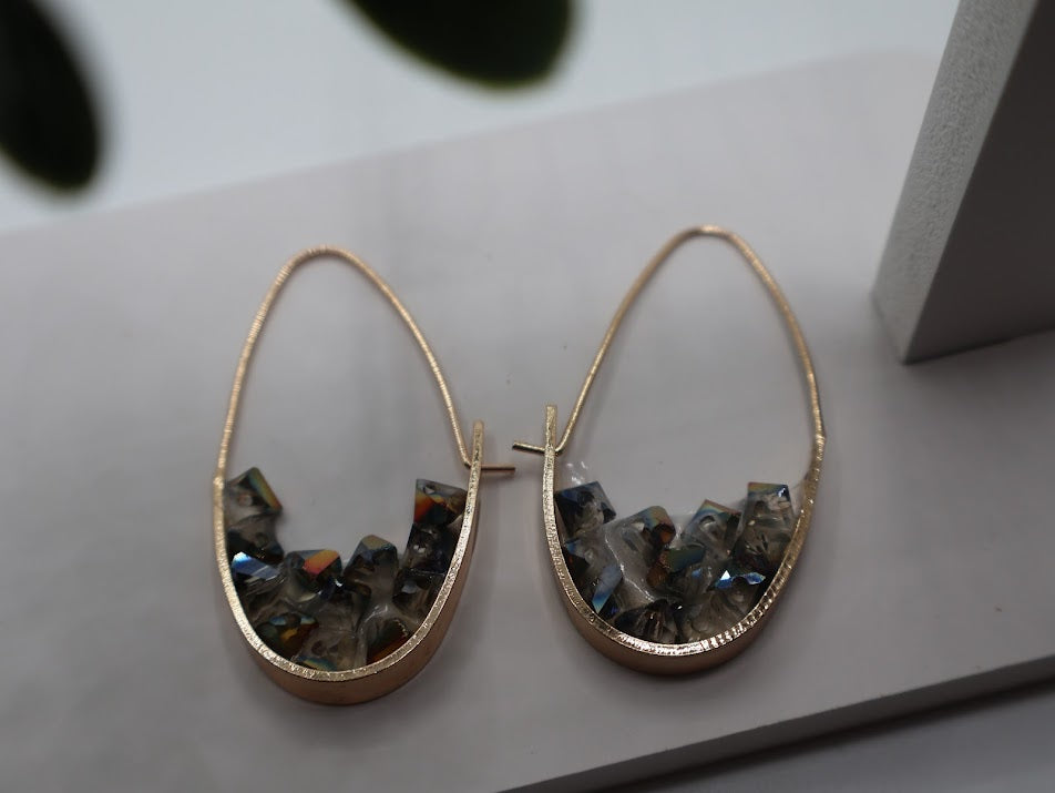 Gold hoop earrings with embedded stones on a light surface