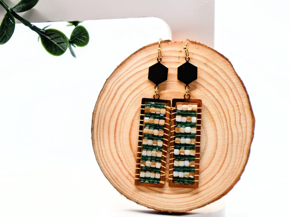 Pair of earrings with geometric design on a wooden block