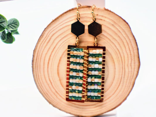 Geometric earrings featuring a unique handwoven design with rich green beads framed in gold.