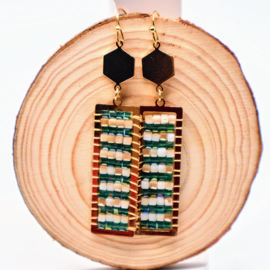 Geometric earrings featuring a unique handwoven design with rich green beads framed in gold.