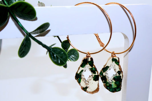 Gold hoop earrings with green and clear teardrop-shaped stone earrings.