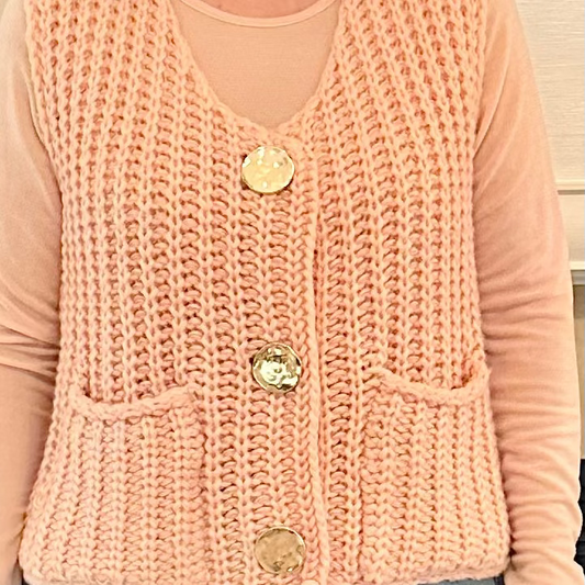 Person wearing a pink knitted vest with buttons