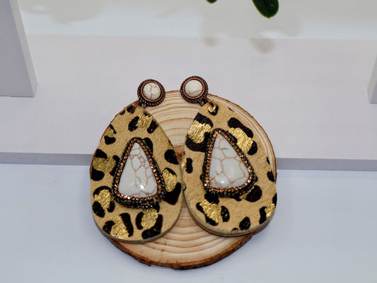 Leopard print earrings with gold accents on a wooden base