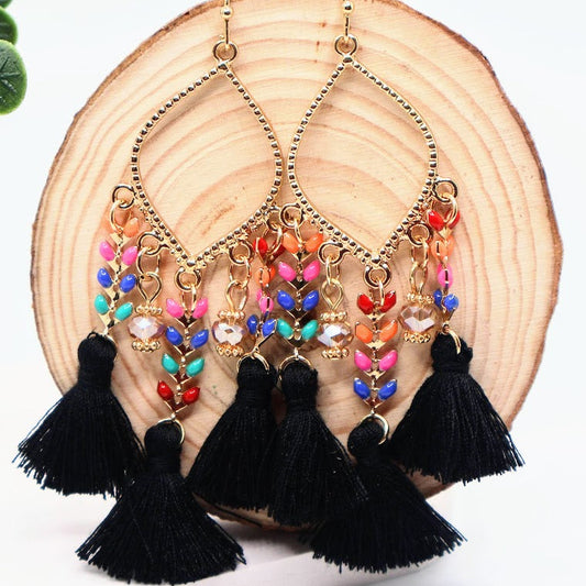 Colorful earrings with tassels on a wooden surface