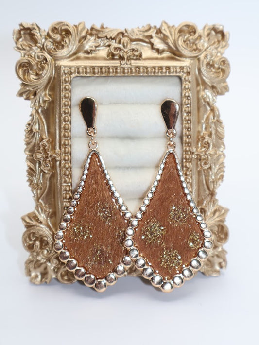 A pair of gold earrings featuring a unique teardrop-inspired design with a rich golden finish, intricate floral accents, and delicate beaded edges.
