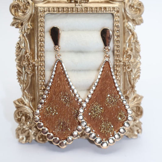 A pair of gold earrings featuring a unique teardrop-inspired design with a rich golden finish, intricate floral accents, and delicate beaded edges.