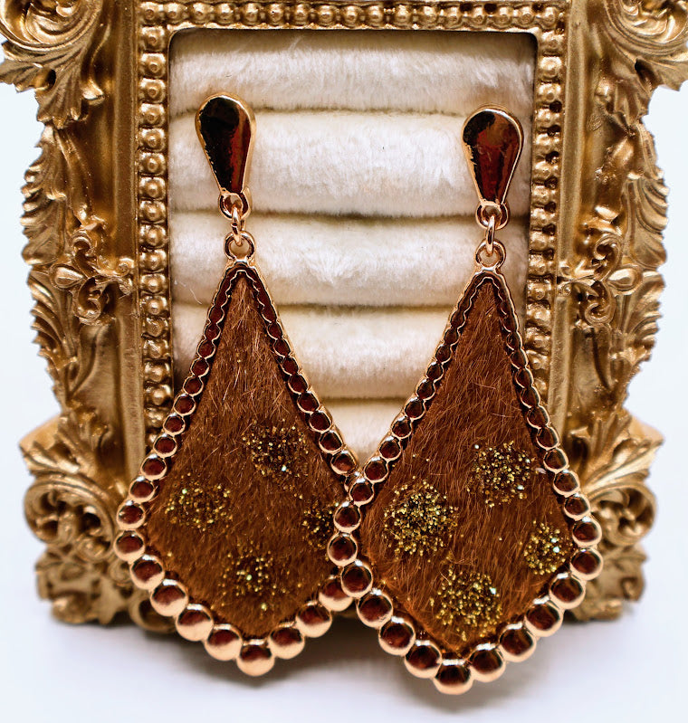Pair of gold earrings with decorative design on a gold stand.