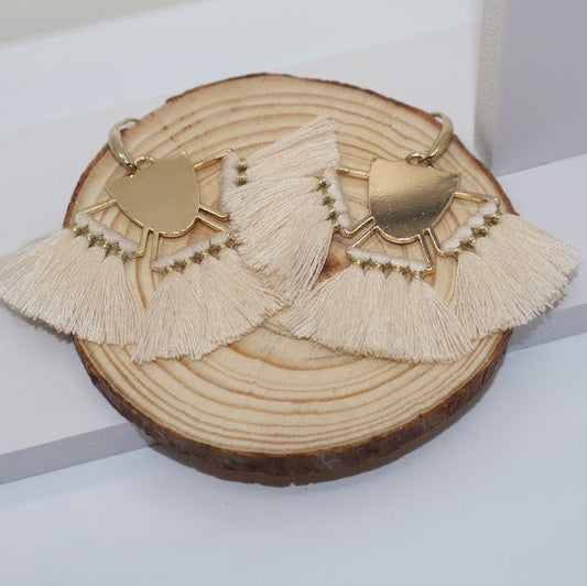 Pair of tassel earrings on a wooden disc with a white background