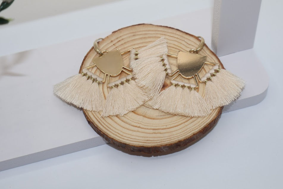Pair of tassel earrings on a wooden disc with a white background