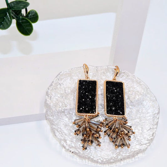 Black and gold earrings on a decorative stand with a white background