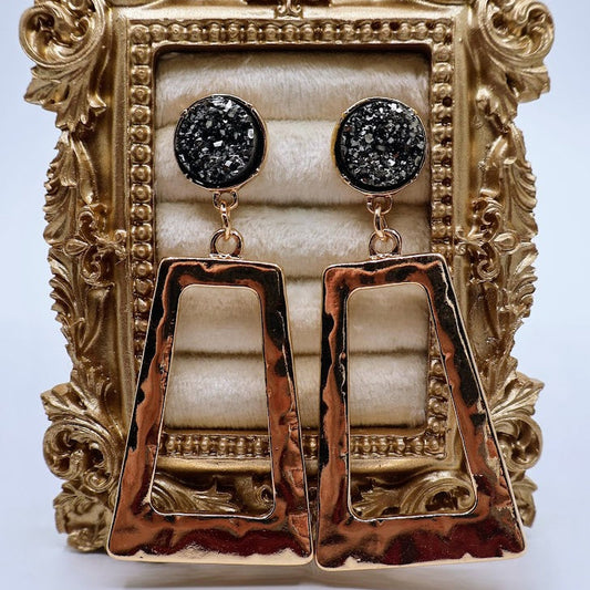 Pair of gold and gray earrings displayed in an ornate gold frame.