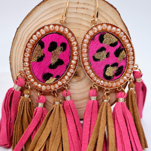 A pair of earrings feature a chic blend of bold pink and earthy brown tassels, elegantly framed by a dazzling gold outline.