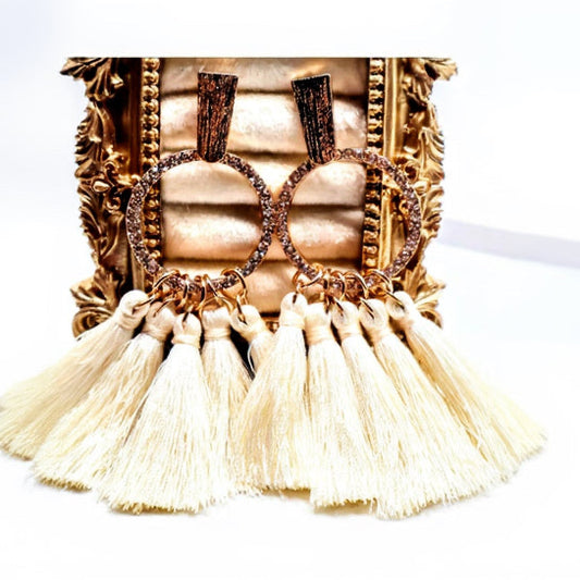 Ivory Tassel Earrings. Featuring soft ivory tassels cascading from a gold-textured hoop adorned with delicate beading.