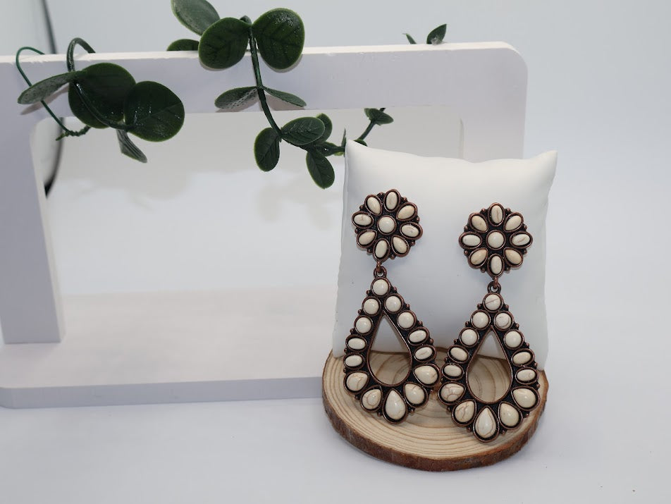 Pair of earrings on a wooden stand with a white background