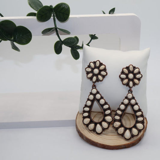 Pair of earrings on a wooden stand with a white background