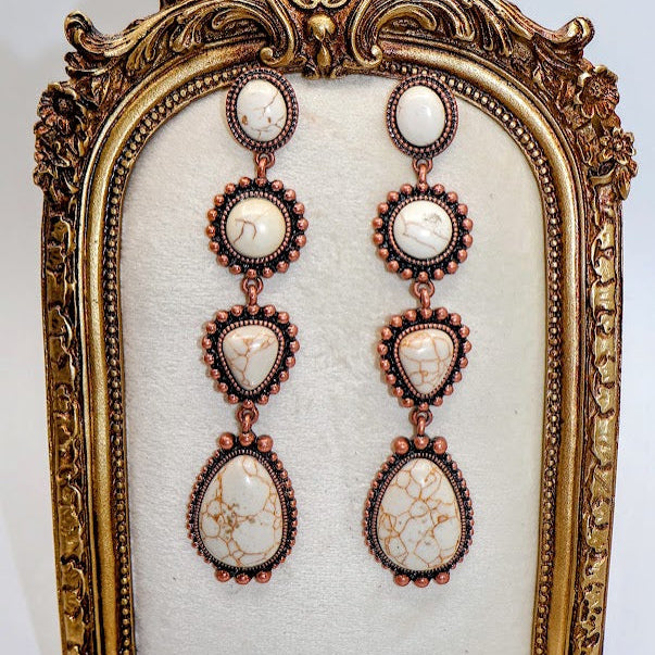 Ornate gold frame with a pair of earrings on a white background