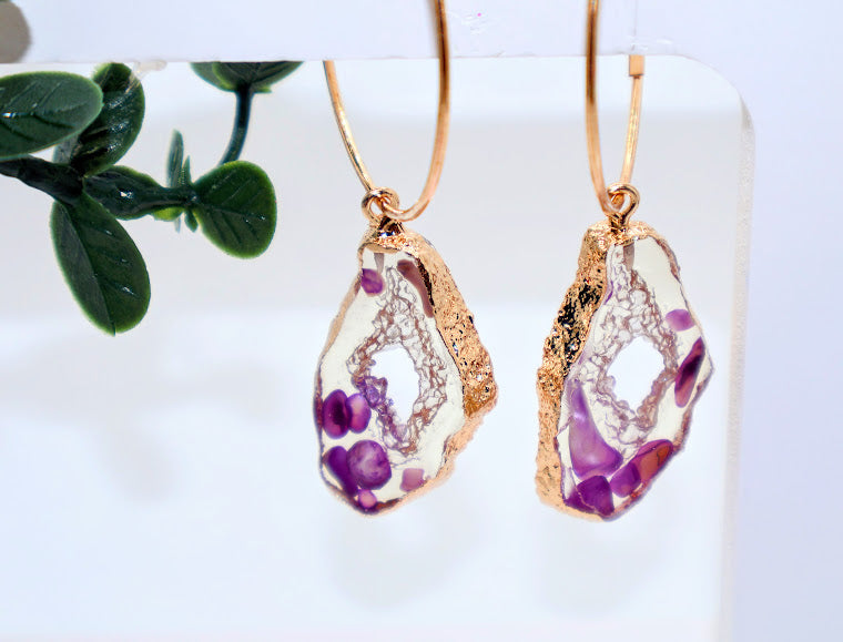 Gold-framed earrings with clear stone shape purple floral incorporated.