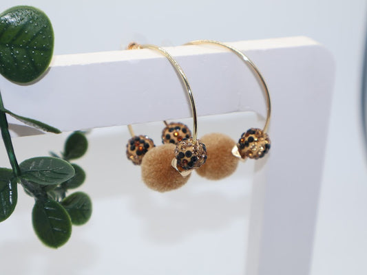 Gold hoop earrings with brown pom-poms and leopard-inspired beads