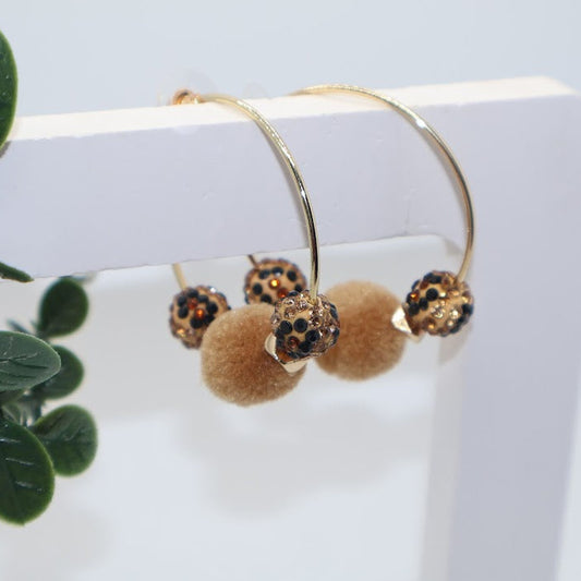 Gold hoop earrings with brown pom-poms and leopard-inspired beads