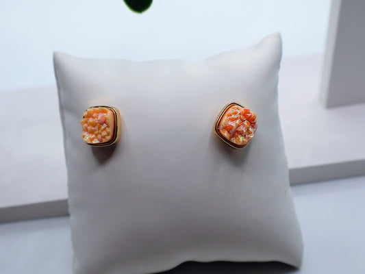 Pair of earrings on a white cushion with a light background