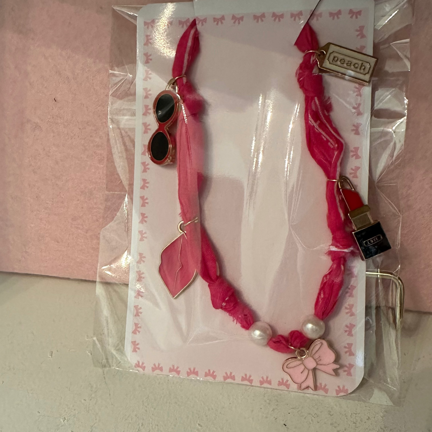 Pink choker necklace with heart pendants against a pink background