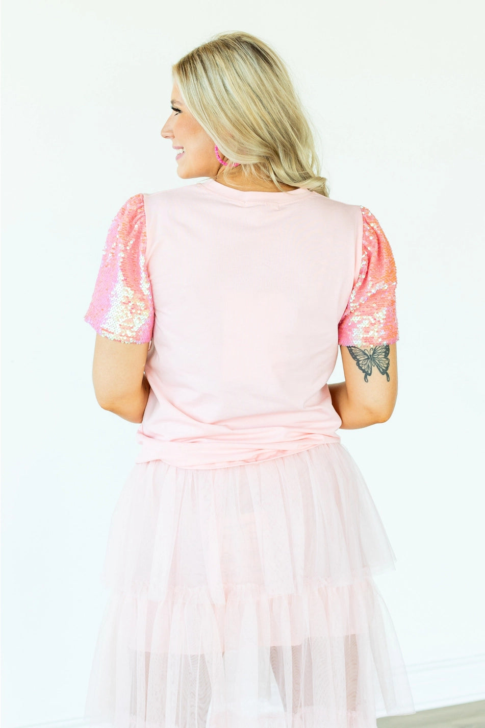 Sequin Sleeve Top is a playful and chic piece that stands out in any wardrobe. Featuring dazzling sequin-lined sleeves and a bold heart graphic.