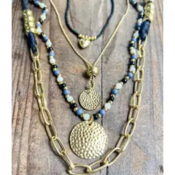Three layered necklaces with gold chains and beaded sections on a wooden surface