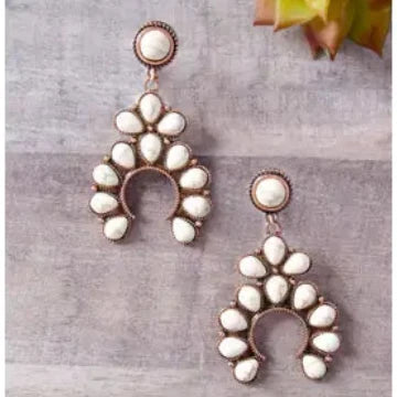 Pair of earrings with white stones on a gray surface