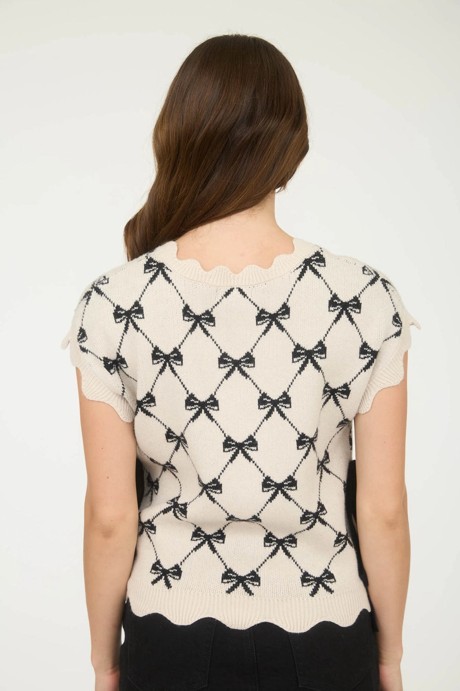 White scallop sweater with black bow pattern.