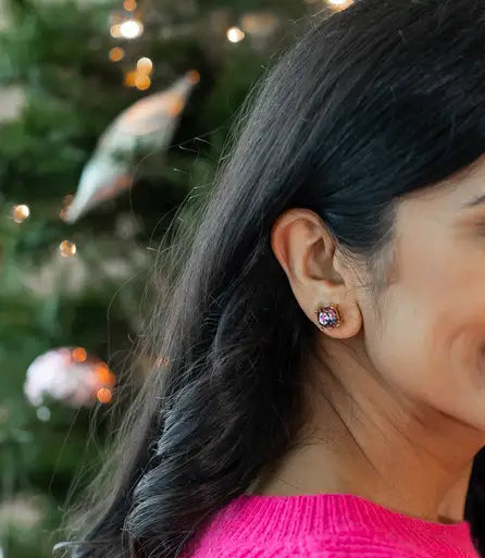Woman wearing a pink sweater with a Christmas tree in the background