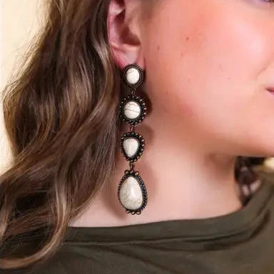 Close-up of a woman wearing a pair of earrings with a neutral background