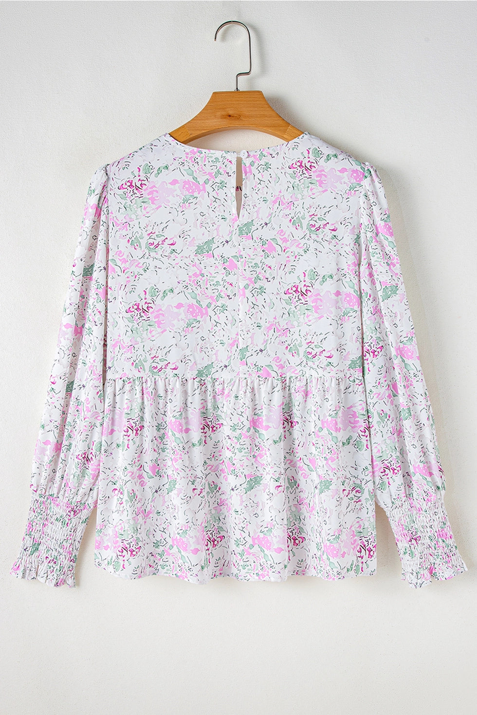 Floral Print Blouse. This blouse features a charming floral print in soft, pastel tones. The design includes a flattering V-neckline, long puffed sleeves with smocked cuffs, and a relaxed, flowy fit.