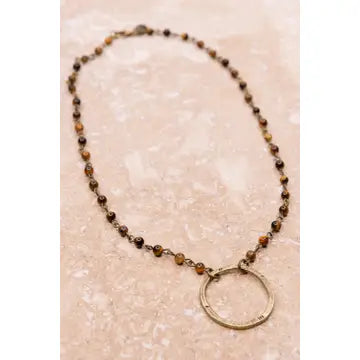 Necklace with beads and a circular pendant on a textured beige background