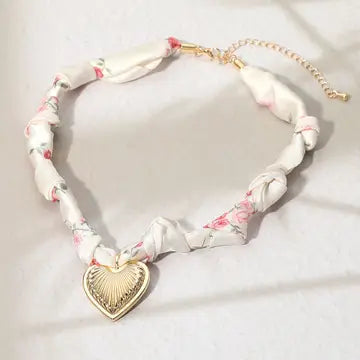 Necklace with floral ribbon and gold heart pendant on a white background