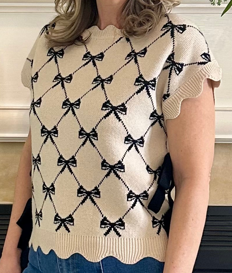 Person wearing a cream-colored sweater with black bow pattern