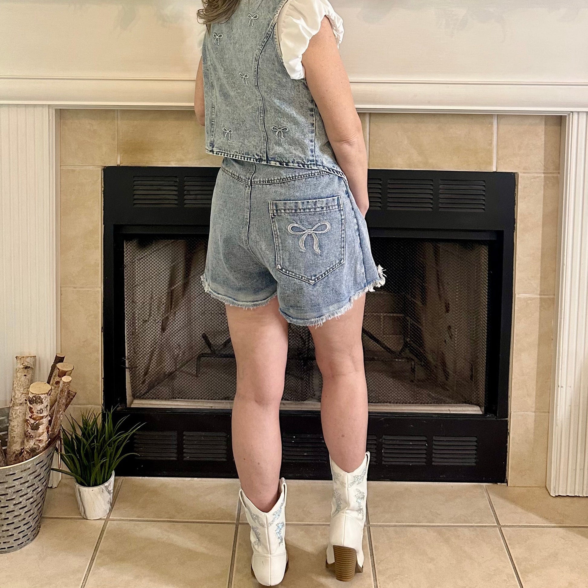 Woman standing in a living room with a fireplace and decorative mantel.