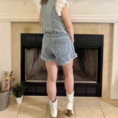 Woman standing in a living room with a fireplace and decorative mantel.