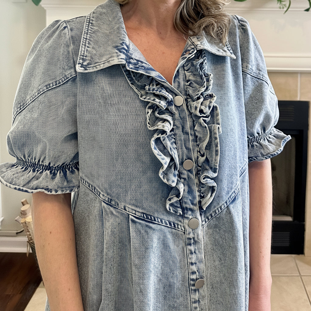 Person wearing a denim dress with ruffled collar and sleeves indoors.
