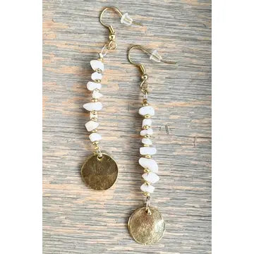Pair of earrings with gold and white stones on a wooden surface