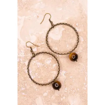 Pair of hoop earrings with circular designs on a beige background