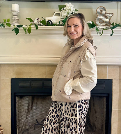 Woman standing in a living room with a fireplace and decorative mantel.